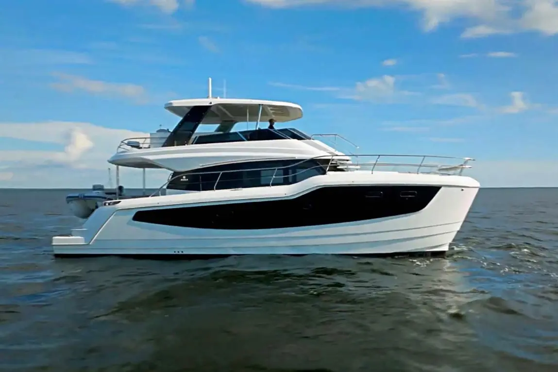 A sleek white and black yacht navigates calm waters under a clear blue sky, showcasing luxury boat design and aesthetics.
